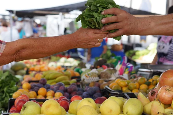 Piyasada, satıcı ve alıcı salata meyve ile sayaç üzerinde elinde mal ve sebze piyasada transferi