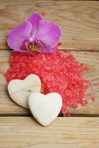 Курортный набор с красной морской солью, ярким цветком орхидеи и камнями в виде сердец . — стоковое фото
