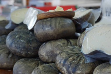 Pazar tezgahın üstünde siyah bir kabuk ile birçok peynir kafa