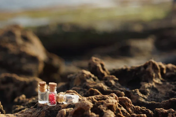 Glasburkar fyllda med proppar, fylld för spa-behandlingar, på klippor nära havet på morgonen — Stockfoto