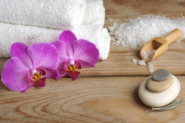 Spa avec sel blanc pour le bain, fleurs d'orchidée et serviettes sur un fond en bois — Photo