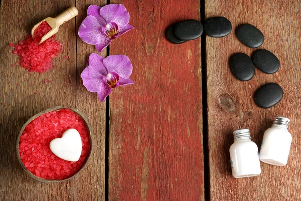 Hindistan cevizi hamamlar, vücut losyonları ve ahşap bir masa üzerinde sıcak masaj için taşlarla kopya alanı metni için orkide, kırmızı tuz ile Spa arka plan