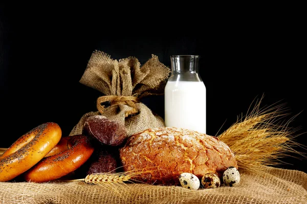 натюрморт с яйцами и молоком. depositphotos 183131450 stock photo different bread and buns on. натюрморт с яйцами и молоком фото. натюрморт с яйцами и молоком-depositphotos 183131450 stock photo different bread and buns on. картинка натюрморт с яйцами и молоком. картинка depositphotos 183131450 stock photo different bread and buns on. Стакан молока, буханка и сноп на черном фоне, с местом для текста