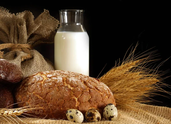 натюрморт с яйцами и молоком. depositphotos 187988424 stock photo still life on a table. натюрморт с яйцами и молоком фото. натюрморт с яйцами и молоком-depositphotos 187988424 stock photo still life on a table. картинка натюрморт с яйцами и молоком. картинка depositphotos 187988424 stock photo still life on a table. Стакан молока, буханка и сноп на черном фоне, с местом для текста