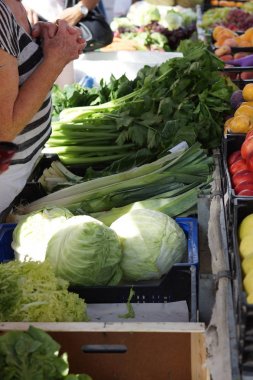 İspanya'da pazarda tezgahta salata ve yeşillik, müşteri bekler, eller, dua gibi