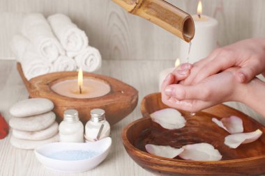 Tablonun üst kısmındaki bir spa paketi ile bambu kök su akışı altında hassas genç eller