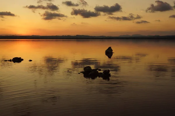 Seenlandschaft bei Sonnenuntergang mit Steinsilhouetten und Spiegelung im Wasser — Stockfoto