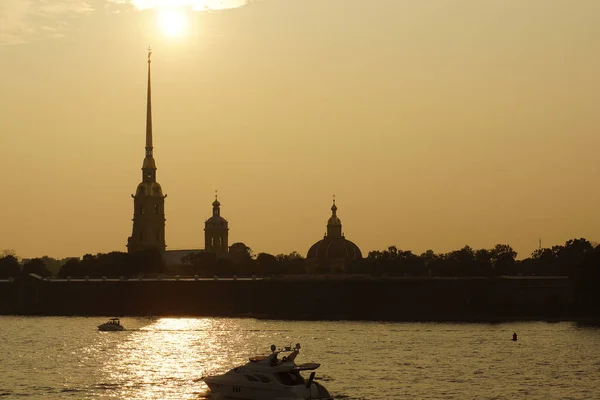 Sylwetka twierdzy Piotra i Pawła w Sankt Petersburgu na tle rzeki Newy i przejeżdżających łodzi z turystami — Zdjęcie stockowe
