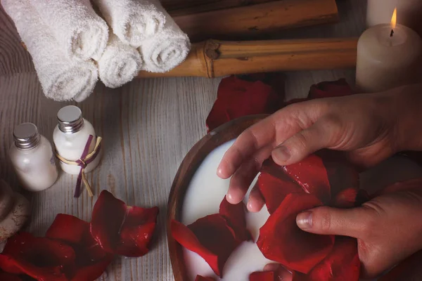Женские руки с лепестками роз во время спа-процедур для кожи — стоковое фото