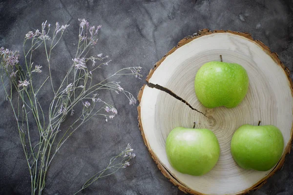 Maçãs verdes em uma redução de uma árvore ao lado de uma flor em uma mesa — Fotografia de Stock