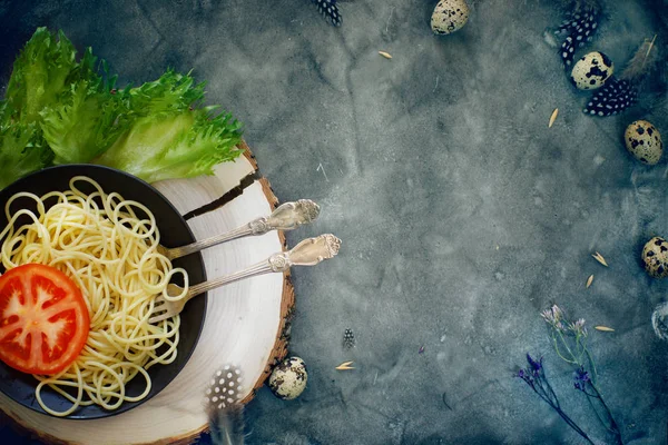 Esparguete italiano em uma chapa com talheres, ao lado de legumes brilhantes e ovos de codorna — Fotografia de Stock