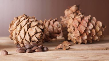 Sedir kozalakları ve bir avuç çam fıstığı ahşap bir masada yatıyor.