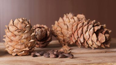 Bir kozalak ve bir avuç çam fıstığı tahta bir masada yatıyor.