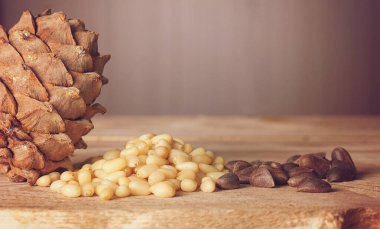 Sedir konisi ve çam fıstığı ahşap bir masada yatıyor.