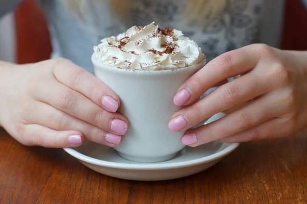 Female hands holding a cup with a cream-covered drink — Stock Photo, Image