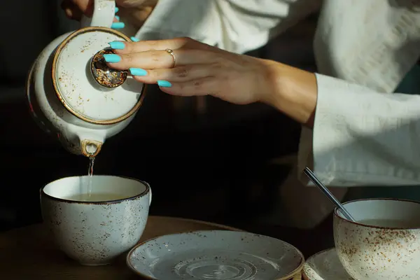 Chica con manicura se vierte té verde de una tetera en un restaurante — Foto de Stock