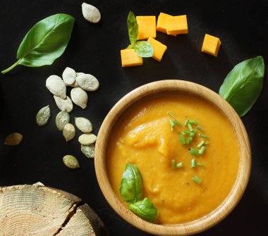 Balkabağı çorbasının üstüne balkabağı çekirdeği ve yeşilliklerin yanına.