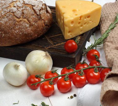 Çavdar ekmeği, peynir, iki soğan ve bir tutam vişneli domates masada karatahtanın üzerinde yatıyor..