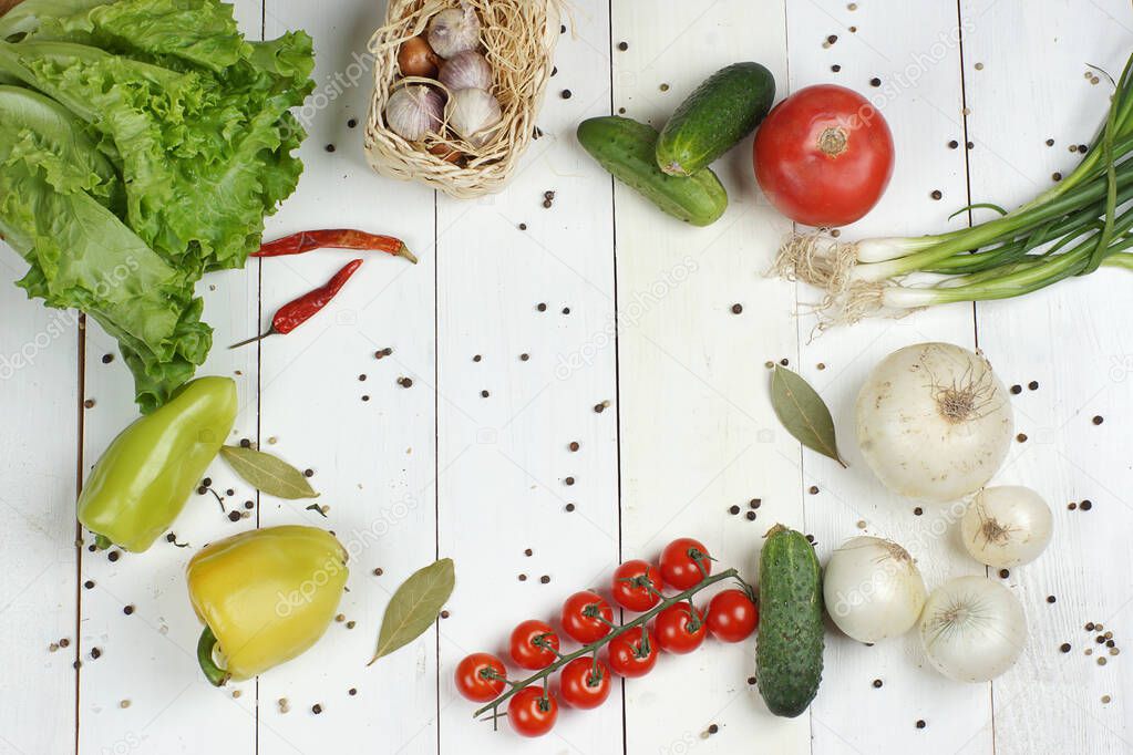 Different vegetables for making salad lie on a white wooden table, top view, frame
