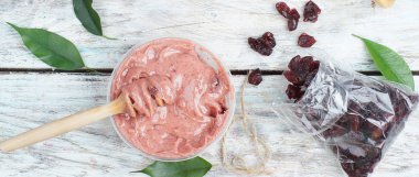 Masanın üzerinde, çırpılmış bal kaşık çevirmeli, kurutulmuş böğürtlen, birkaç yeşil yaprak.