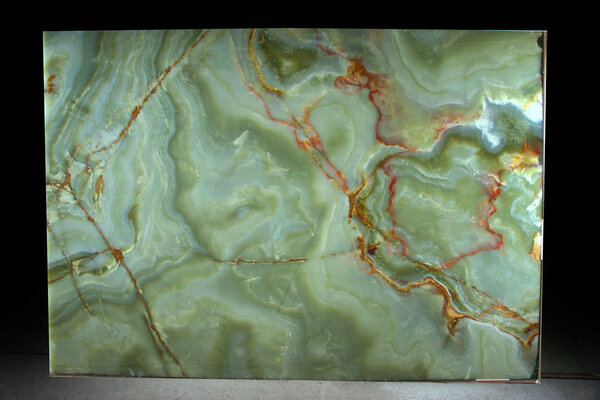 A large slab of natural green stone with red veins is called Verde Onix