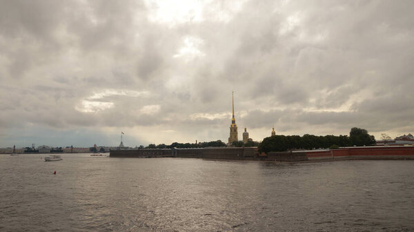 Peter and Paul Fortress is one of the attractions in the city of St. Petersburg in Russia. The evening sky is reflected in the Neva River, pleasure excursion boats sail by