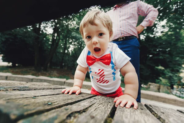 Niño pequeño se inclina sobre el banco de madera —  Fotos de Stock