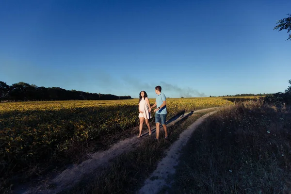 Man en zwangere vrouw lopen in de weide — Stockfoto