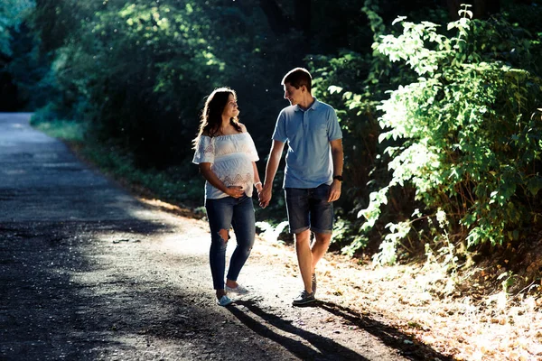 Uomo e donna incinta che camminano nel parco — Foto Stock