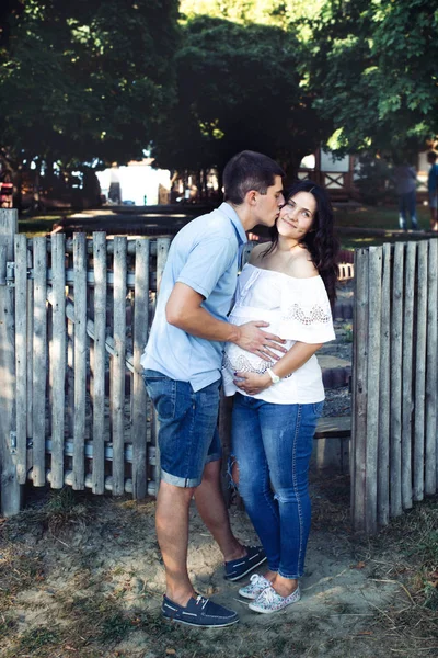 Uomo e donna incinta vicino alla recinzione in legno — Foto Stock