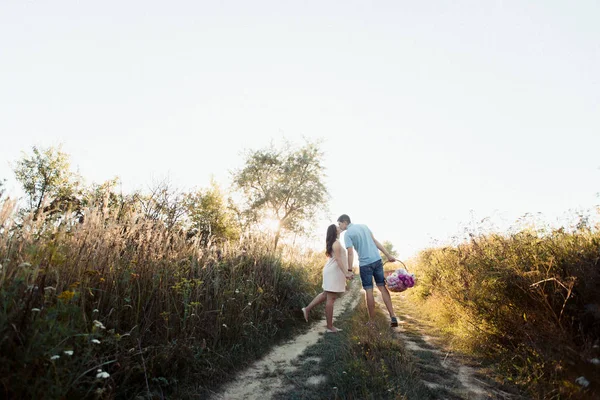 Uomo e donna incinta che camminano sul campo — Foto Stock