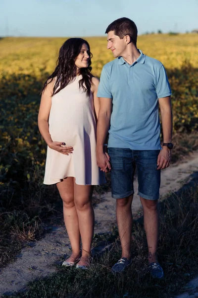 人と妊娠中の女性が草原を歩いて — ストック写真