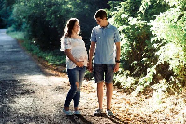 Mann und schwangere Frau gehen im Park spazieren — Stockfoto