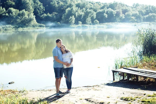 Мужчина и беременная женщина возле озера — стоковое фото