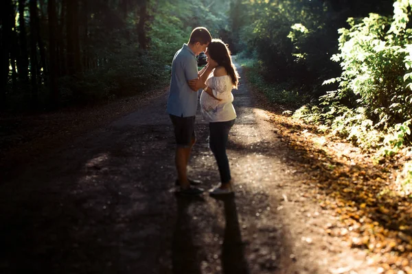 Man och gravid kvinna promenader i parken — Stockfoto