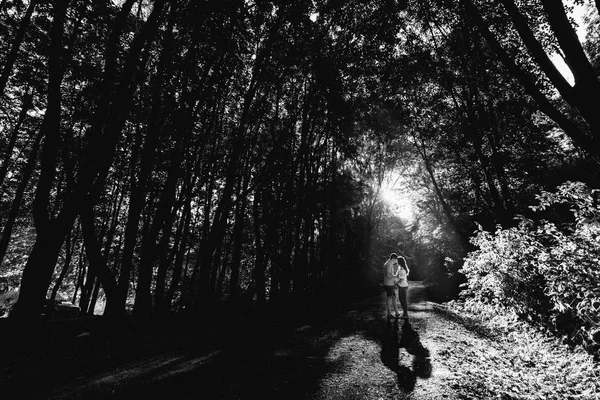 Man och gravid kvinna promenader i parken — Stockfoto