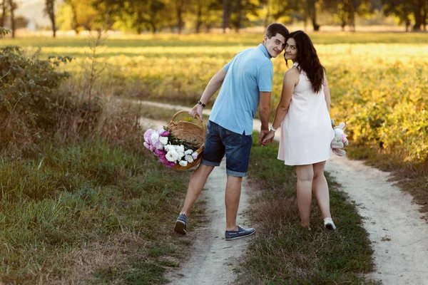 Uomo e donna incinta che camminano nel prato — Foto Stock