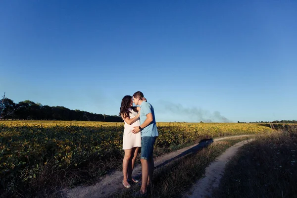 Man och gravid kvinna promenader i äng — Stockfoto