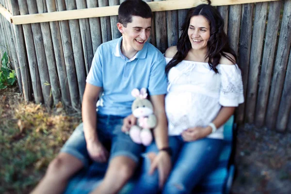 Hombre y mujer embarazada cerca de valla de madera — Foto de Stock