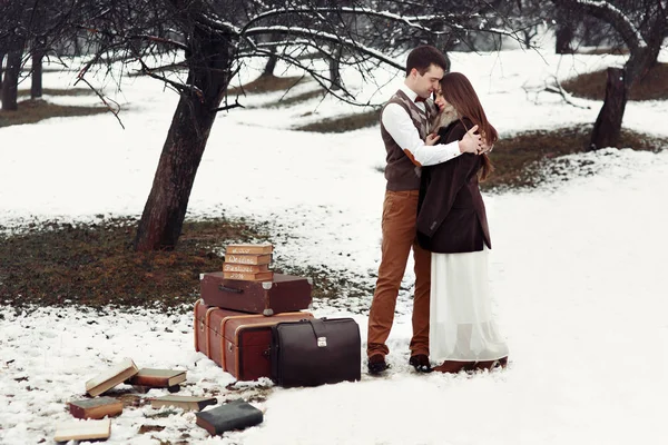 Pareja cariñosa con maletas en el parque de invierno —  Fotos de Stock