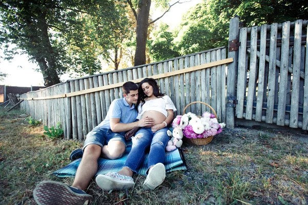 Man och gravid kvinna nära trästaket — Stockfoto