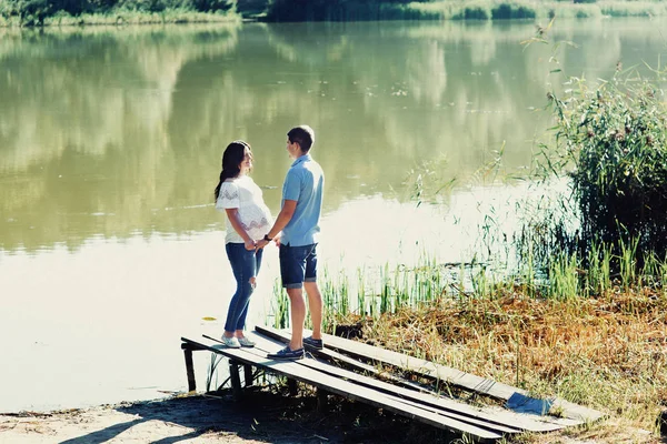 Uomo e donna incinta vicino al lago — Foto Stock