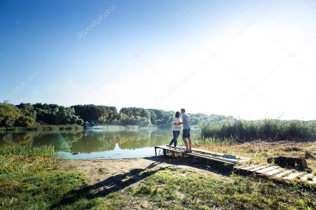 Man and pregnant woman near lake