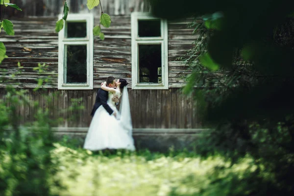 Bride and groom by old wooden house — Stock Photo, Image