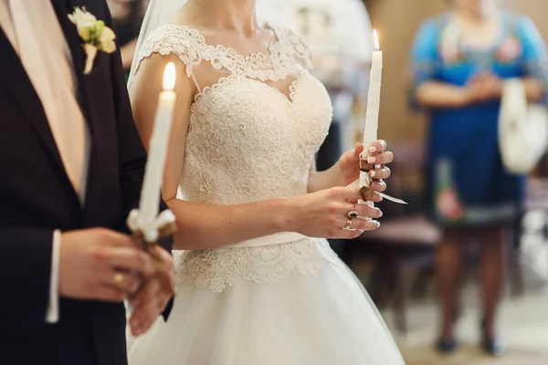 Новобрачные держат свечи в церкви — стоковое фото