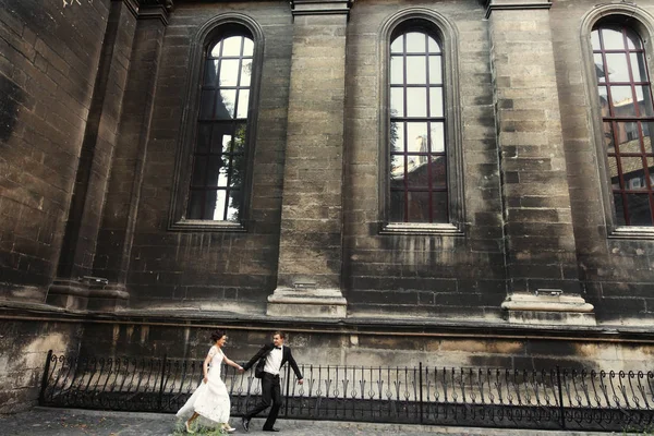 Jonggehuwden op een wandeling in de buurt van oud gebouw — Stockfoto