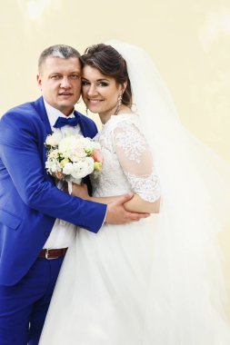 Bej renkli duvar tarafından çarpıcı yeni evliler