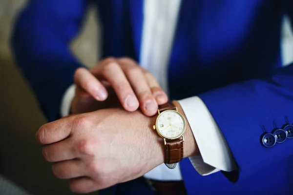 Man touches watch with leather bracelet