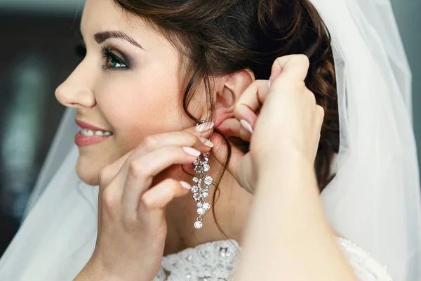 Mooie bruid zet op sprankelende earring — Stockfoto