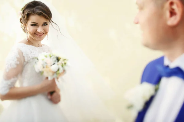 Prachtige jonggehuwden door beige muur — Stockfoto